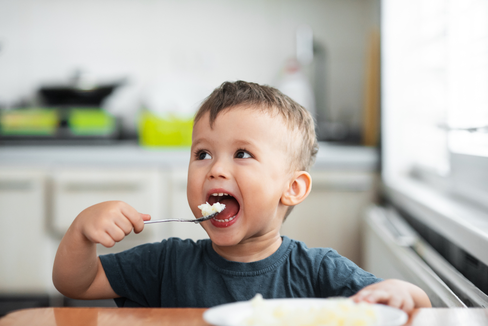 The,Little,Boy,In,The,Kitchen,Eagerly,Eating,Rice,With